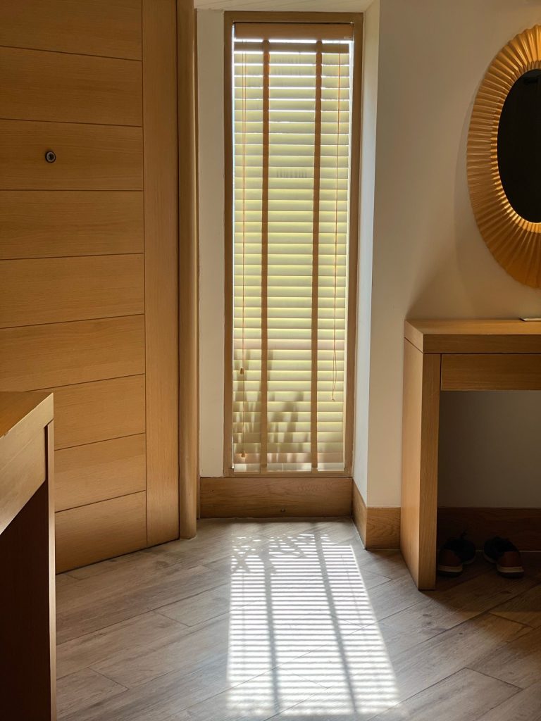 Minimalist interior with natural light streaming through window blinds, creating a serene ambiance.