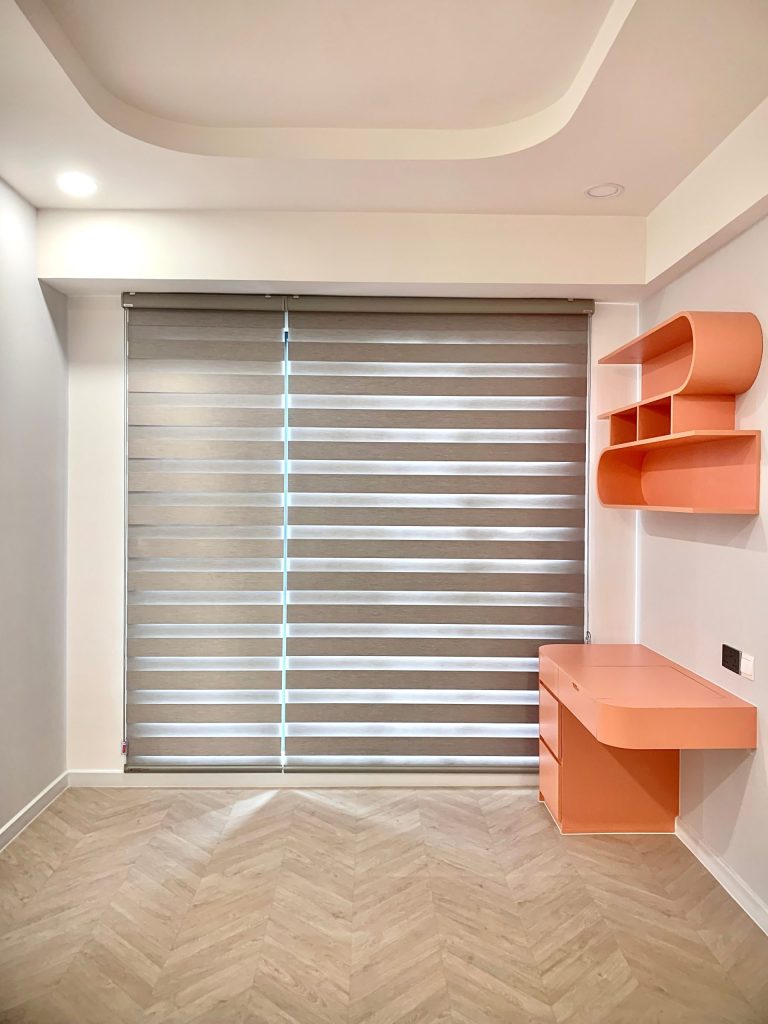 Bright minimalist room with a modern orange desk and striped blinds.