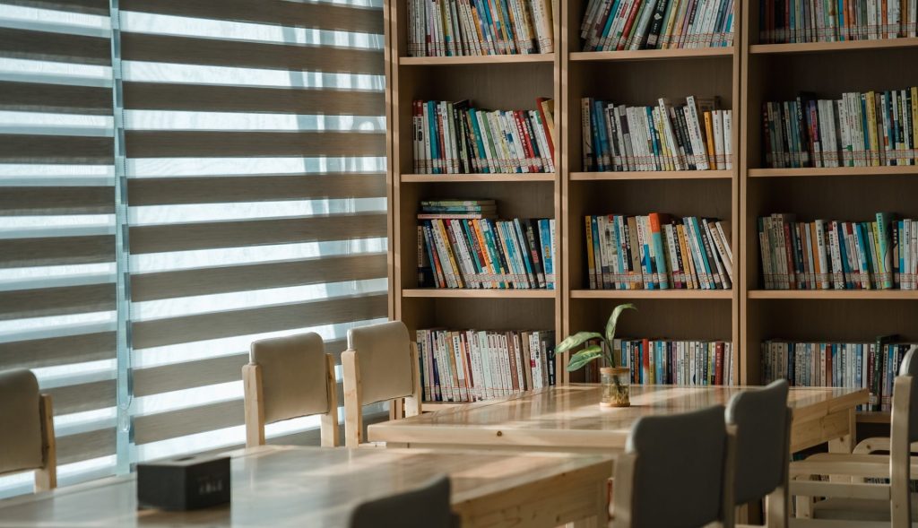Warm and inviting library space featuring bookshelves and wooden tables ideal for study.