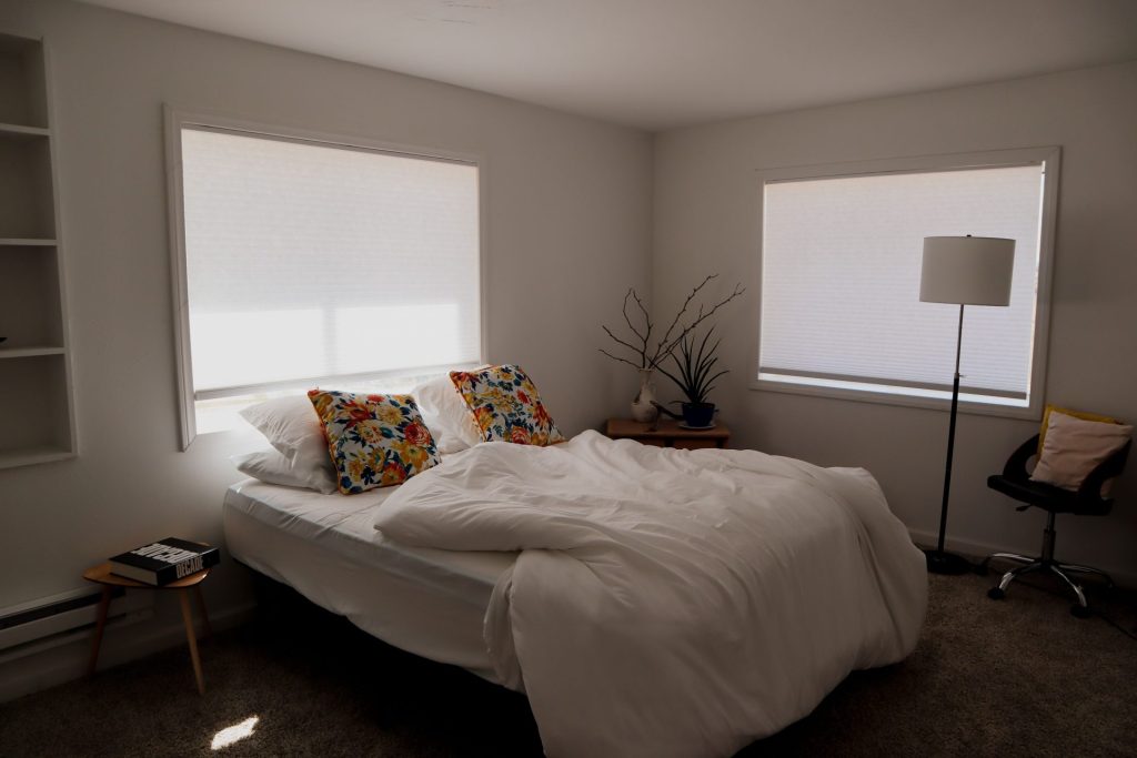 Bright and inviting modern bedroom with floral pillows and natural light.